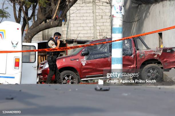 Police officer talks by his phone next to an exploded car after multiple attacks aimed on police forces resulted in at two officers killed on...