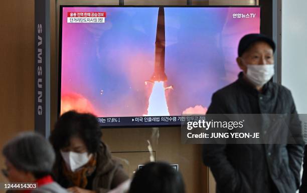 People watch a television screen showing a news broadcast with file footage of a North Korean missile test, at a railway station in Seoul on November...