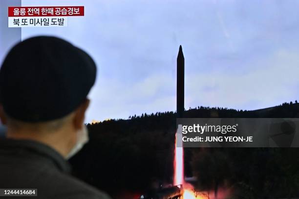 Man watches a television screen showing a news broadcast with file footage of a North Korean missile test, at a railway station in Seoul on November...