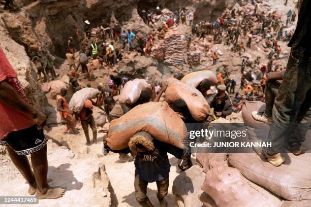 Artisanal miners carry sacks of ore at the Shabara artisanal mine near Kolwezi on October 12, 2022. - Some 20,000 people work at Shabara, in shifts...