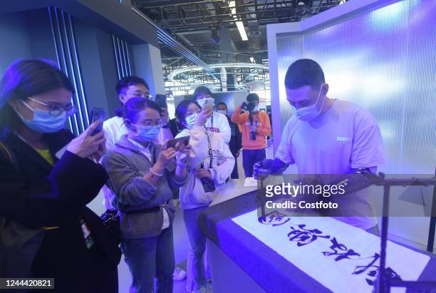 Members of the media watch a "bionic robotic hand" developed based on brain-computer interface writing calligraphy with a brush during the upcoming...