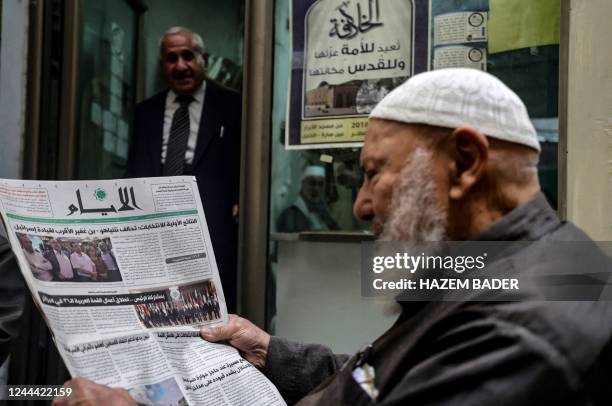 Palestinian man reads the headlines of a local newspaper featuring the Israeli legislative at a shop in the occupied-West Bank city of Hebron, on...