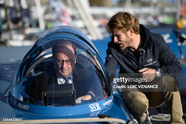 French former president Francois Hollande talks to French skipper Francois Gabart aboard his Ultim multihull SVR - Lazartigue at the 'Village de...