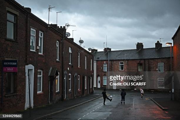 Children play football outside a row of terraced homes on a residential street in Oldham, northern England on November 2, 2022.