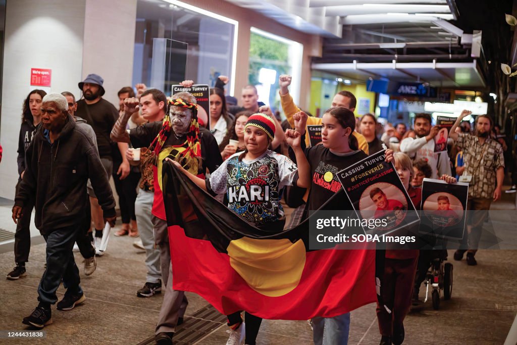 Protesters march with flags and Cassius Turvey portraits...