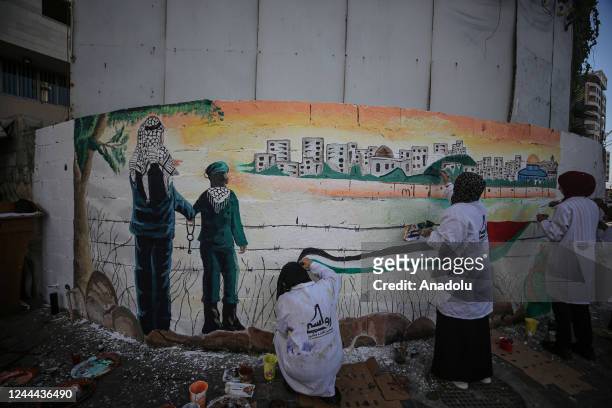 Palestinian artists draw pictures on the wall, describing the right of Palestinians to return to their homeland, on the 105th anniversary of the...