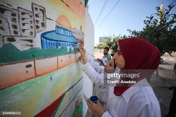 Palestinian artists draw pictures on the wall, describing the right of Palestinians to return to their homeland, on the 105th anniversary of the...