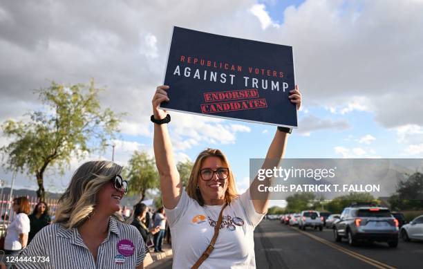 Person holds a sign that reads "Republican Voters Against Trump Endorsed Candidates" as people wait in line to enter a "Get Out the Vote" rally at...