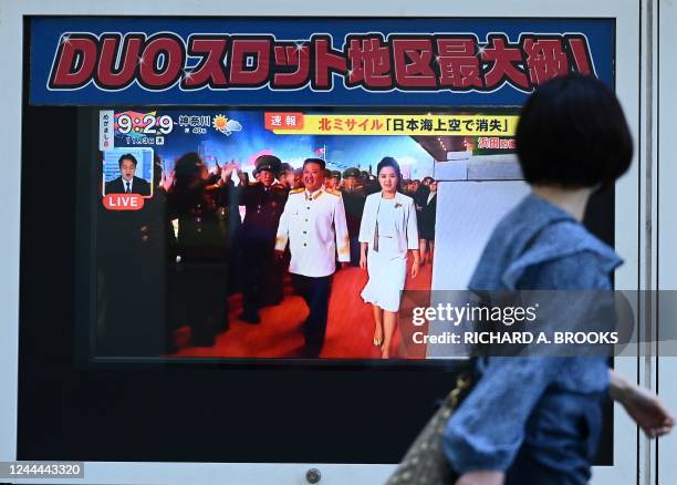 Woman walks past a television screen showing a news report about the latest North Korean missile launch with images of the North's leader, Kim Jong...