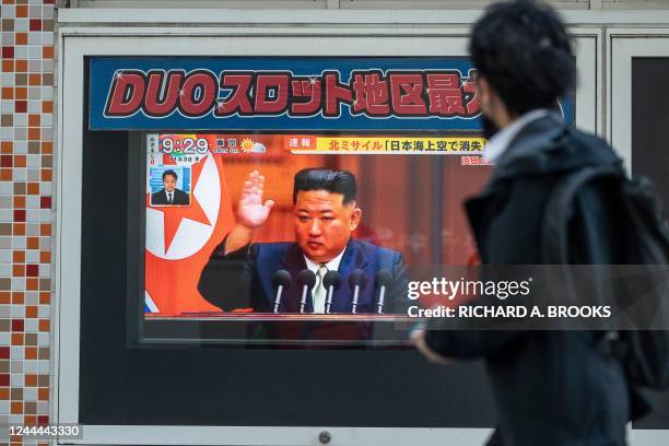 Man walks past a television screen showing a news report about the latest North Korean missile launch with images of the North's leader, Kim Jong Un,...