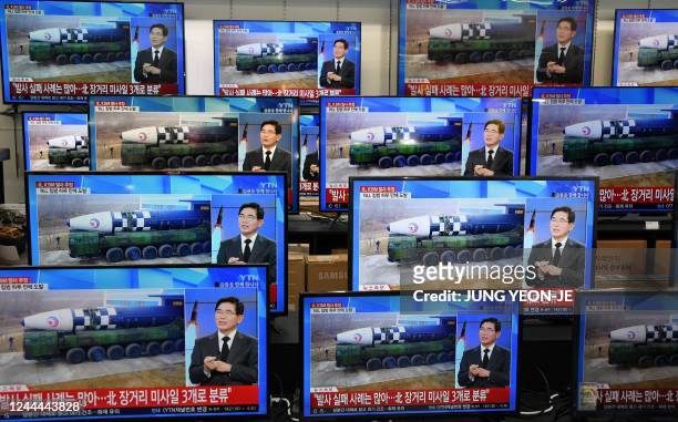 Television screens show a news report about the latest North Korean missile launch with file footage of a North Korean missile, at an electronic...