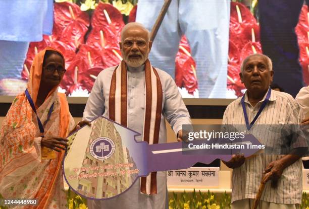 Prime Minister Narendra Modi with Union Minister Hardeep Singh Puri and LG Delhi Vinoy Kumar Saxena , present Home key to a beneficiary during the...