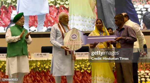 Prime Minister Narendra Modi with Union Minister Hardeep Singh Puri and LG Delhi Vinoy Kumar Saxena , present Home key to a beneficiary during the...