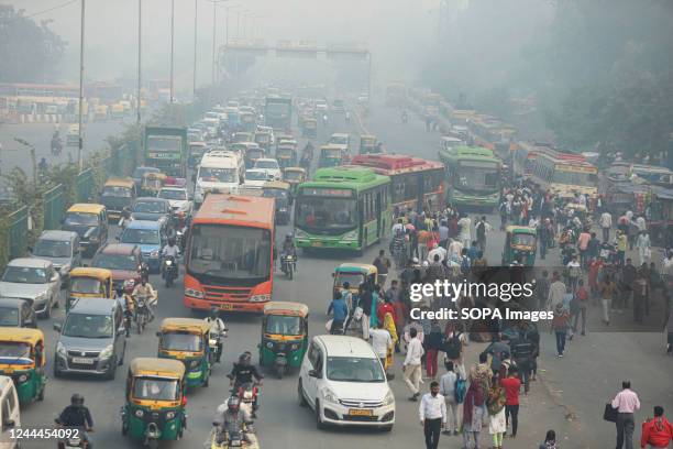 Commuters wait for the bus outside the Anand Vihar bus terminal on a smoggy day amid deteriorating air quality levels. The air quality index stood at...