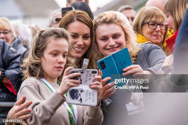 Catherine, Princess of Wales poses for photos with the public as she arrives to visit "The Street" with Prince William, Prince of Wales during their...