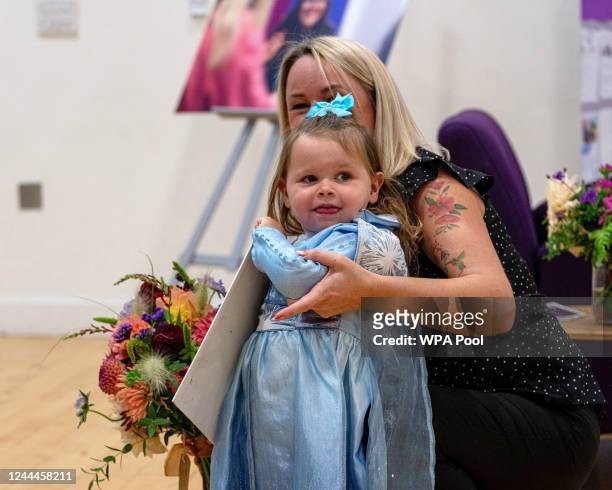 Young girl waits with some flowers for Catherine, Princess of Wales and Prince William, Prince of Wales to visit "The Street" for their official...