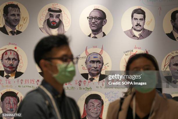 People stand in front of a collaborative art piece representing dictators ahead of the Oslo freedom forum in Taipei.