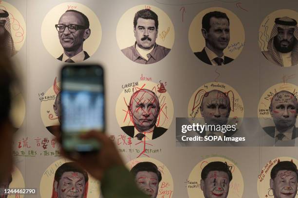 Person takes a picture of a collaborative art piece representing dictators ahead of the Oslo freedom forum in Taipei.