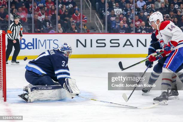 Nick Suzuki of the Montreal Canadiens chips the puck over goaltender Connor Hellebuyck of the Winnipeg Jets for a first period goal at the Canada...