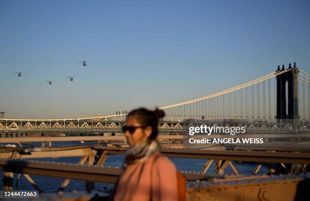 Helicopters fly in the distance as people cross the Brooklyn Bridge in New York on November 3, 2022.