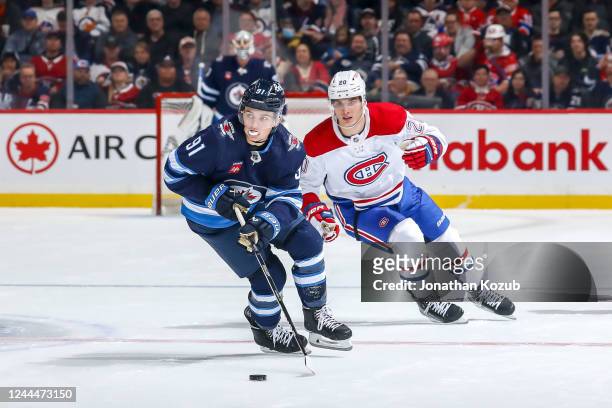 Cole Perfetti of the Winnipeg Jets plays the puck down the ice as Juraj Slafkovsky of the Montreal Canadiens gives chase during second period action...