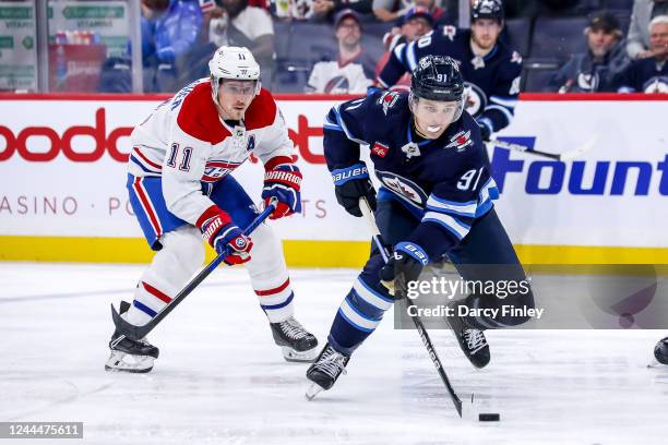 Cole Perfetti of the Winnipeg Jets plays the puck down the ice as Brendan Gallagher of the Montreal Canadiens gives chase during third period action...