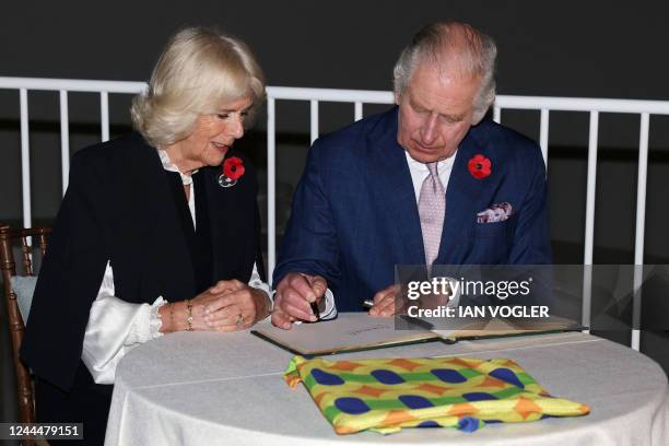 Britain's King Charles III and Britain's Camilla, Queen Consort sign a visitor's book at the Victoria and Albert Museum, during a visit to the Africa...