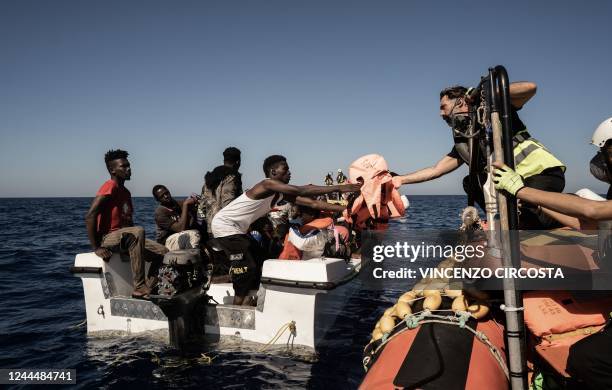 Rescuer hands a life jacket to a migrant as migrants prepare to get on board the Ocean Viking ship sailing in the international waters off Libya in...