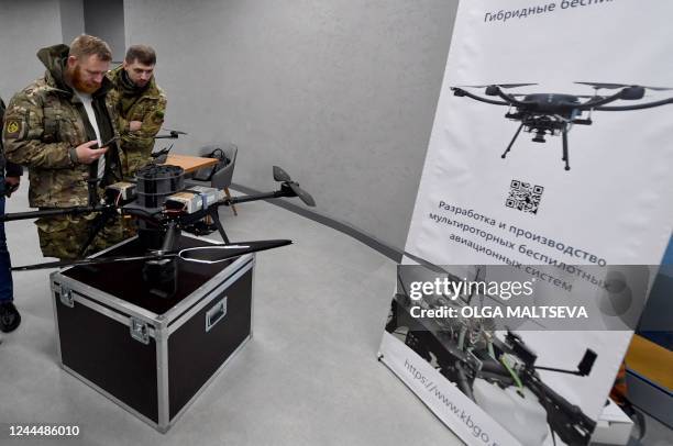 People wearing military camouflage look at drones on display in an exhibition in the 'PMC Wagner Centre', associated with the founder of the Wagner...