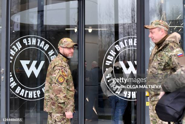 Visitors wearing military camouflage stand at the entrance of the 'PMC Wagner Centre', associated with the founder of the Wagner private military...