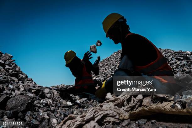 Workers sort through crushed rocks containing chromite, before to goes through a process to refine and extract the ore that yields chromium, a vital...