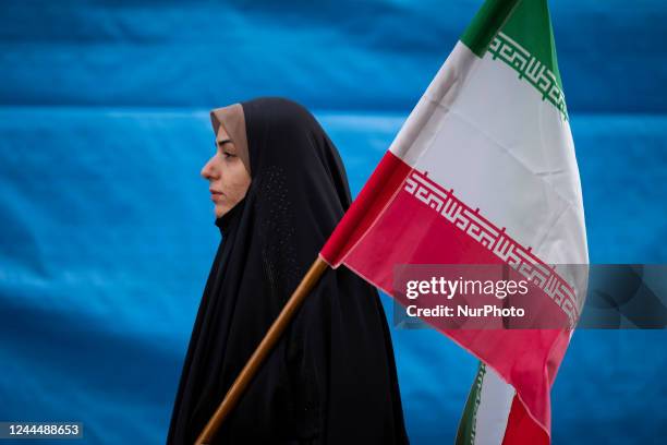 Veiled Iranian woman carrying an Iran flag while attending a gathering out of the former U.S. Embassy in Tehran to mark the anniversary of the...