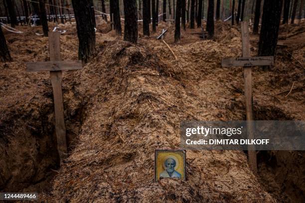 This photograph taken on November 4 shows an Orthodox icon placed at empty graves after the exhumation of bodies from mass graves dug during the...