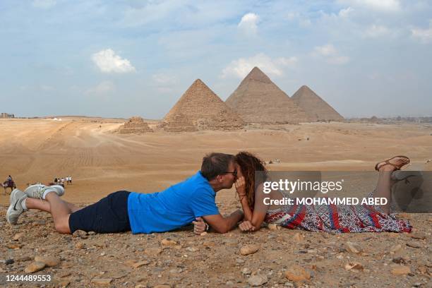 Spanish couple kisses in front of the Great Pyramid of Khufu, the Pyramid of Khafre, and the Pyramid of Menkaure, at the Giza Pyramids Necropolis on...