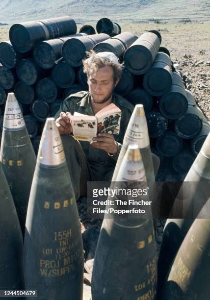 An Israeli soldier reading amidst a pile of shells during the Yom Kippur War, circa October 1973.