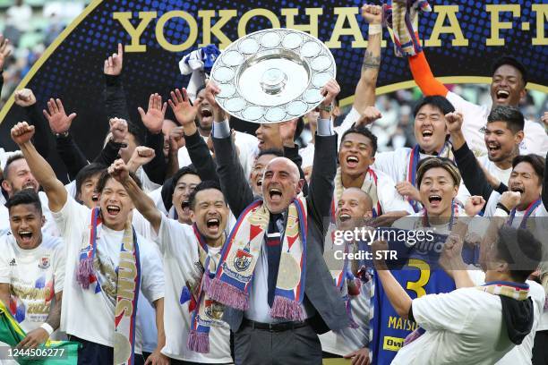 Yokohama F Marinos manager Kevin Muscat holds up the trophy as he celebrates with teammates after taking Japan's professional J-League football title...
