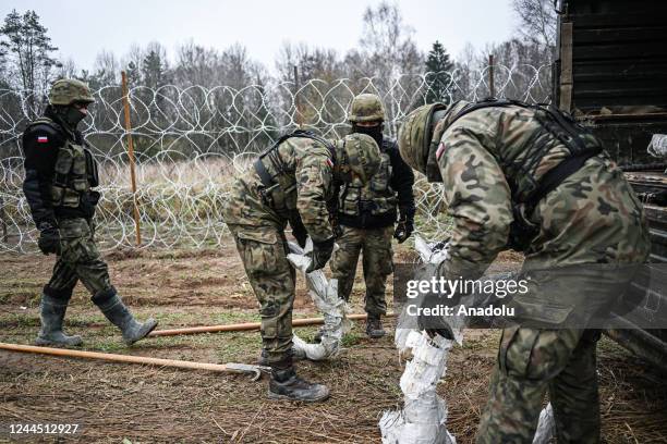 Soldiers of the Polish army carry barbed wire as they construct a barrier on Poland's- Russian exclave Kaliningrad border on November 05, 2022 in...