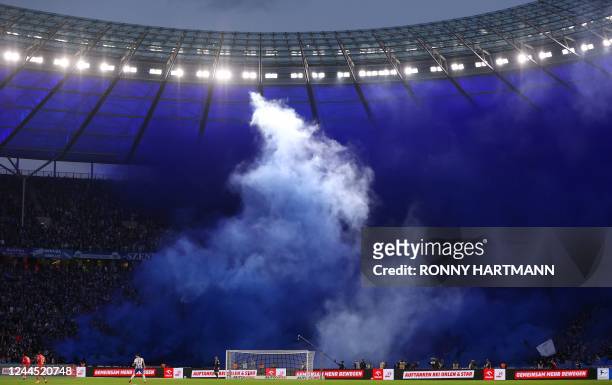 Supporters of Hertha Berlin light flares as clouds of smoke disrupt visibility on the pitch during the German first division Bundesliga football...