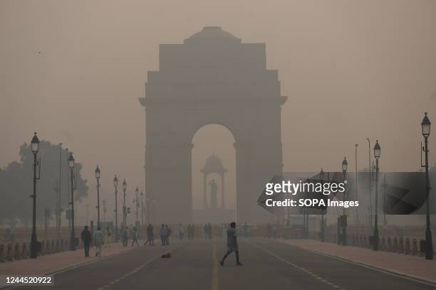 Pedestrians walk along a road near the India Gate amid heavy smog in New Delhi. Delhi's air quality remains "severe", accounting for 30 per cent of...