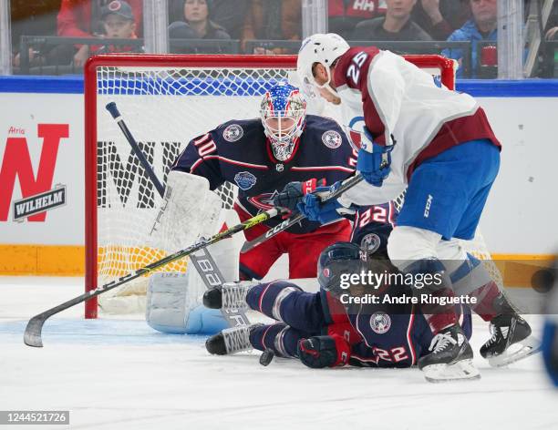 Logan O'Connor of Colorado Avalanche battles for puck possession against Jake Bean of the Columbus Blue Jackets in front of Joonas Korpisalo during...