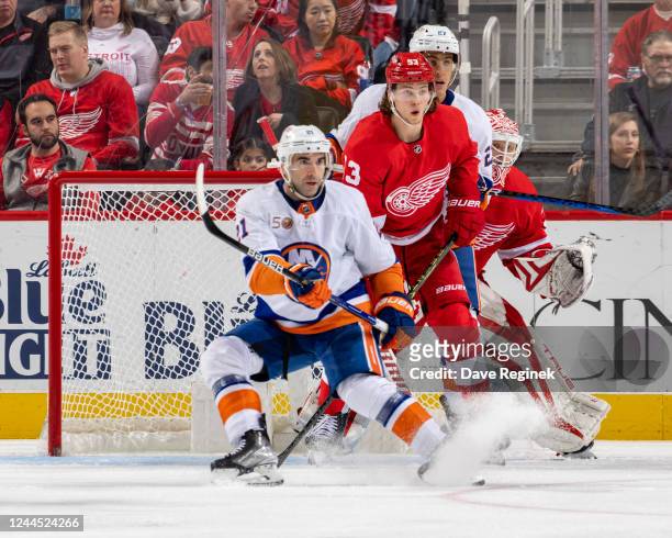 Ville Husso of the Detroit Red Wings looks around teammate Moritz Seider as well as Anders Lee and Kyle Palmieri of the New York Islanders in front...