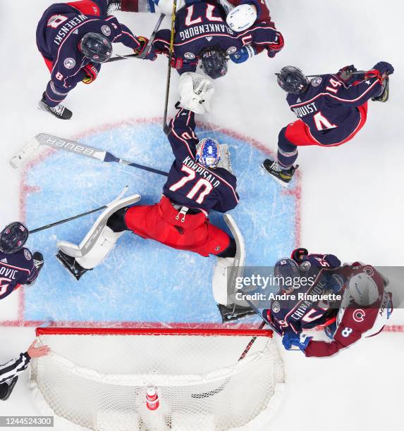 Joonas Korpisalo of the Columbus Blue Jackets covers a loose puck in front of the net, surrounded by teammates during the 2022 NHL Global Series...