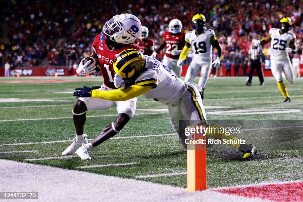 Aron Cruickshank of the Rutgers Scarlet Knights makes a catch for a first down as Mike Sainristil of the Michigan Wolverines tackles him out of...