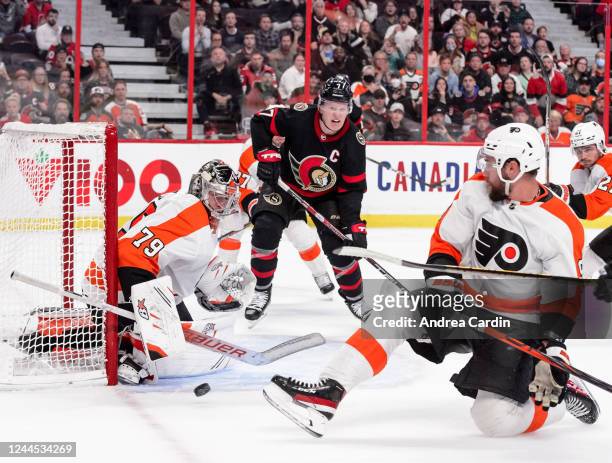 Ivan Provorov of the Philadelphia Flyers blocks a shot as Carter Hart tends net and Brady Tkachuk of the Ottawa Senators tracks the loose puck at...