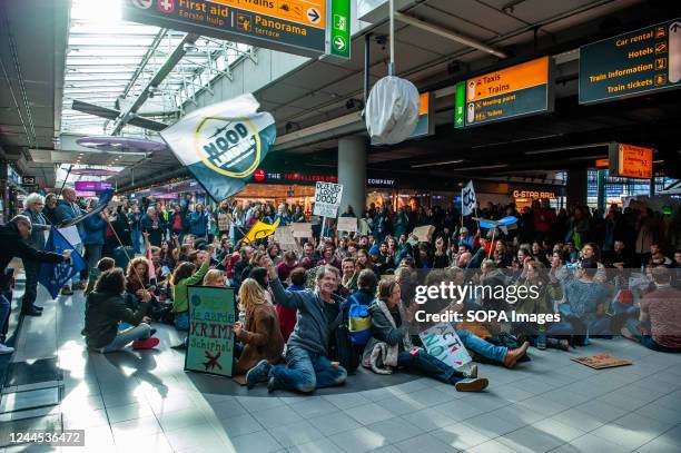 Activists sitting on the main hall of the airport are seen holding flags and placards against the flight industry during the demonstration. Hundreds...