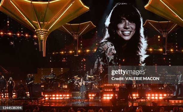 Singer Olivia Rodrigo performs under a photo of Carly Simon, on stage during the 37th Annual Rock and Roll Hall of Fame Induction Ceremony at the...