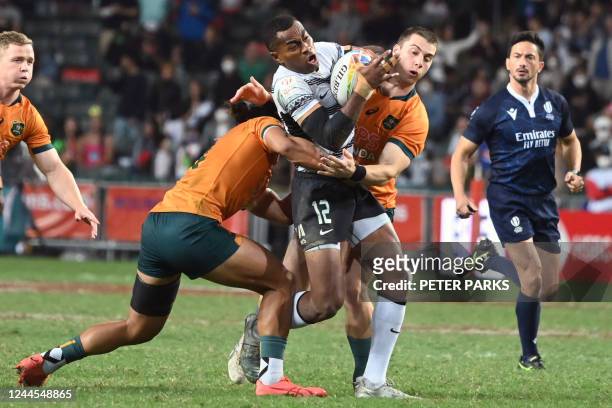 Fijis Vuiviawa Naduvalo is tackled by Australias Dietrich Roache and Henry Paterson in the Cup final at the Hong Kong Sevens rugby tournament on...