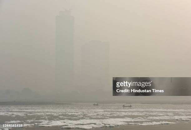 Fishermen ride through a polluted Yamuna river on a smog-filled morning, on November 5, 2022 in New Delhi, India.