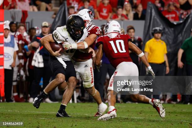 Drake Thomas of the North Carolina State Wolfpack sacks Sam Hartman of the Wake Forest Demon Deacons at Carter-Finley Stadium on November 5, 2022 in...