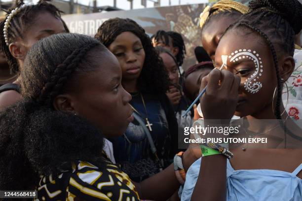 Fans wait to get decorative face paint before the premiere of "Black Panther: Wakanda Forever" in Lagos, on November 6, 2022. - The African premiere...